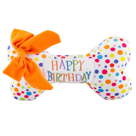 A dog playing with the Haute Diggity Dog Happy Birthday Bone plush squeaker toy during a birthday celebration.