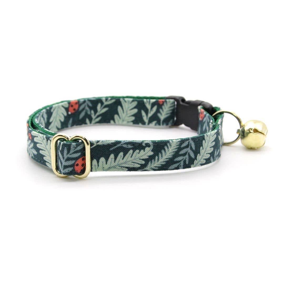 Made By Cleo Eden green cat collar displayed on wooden surface showing breakaway buckle and fabric pattern details.