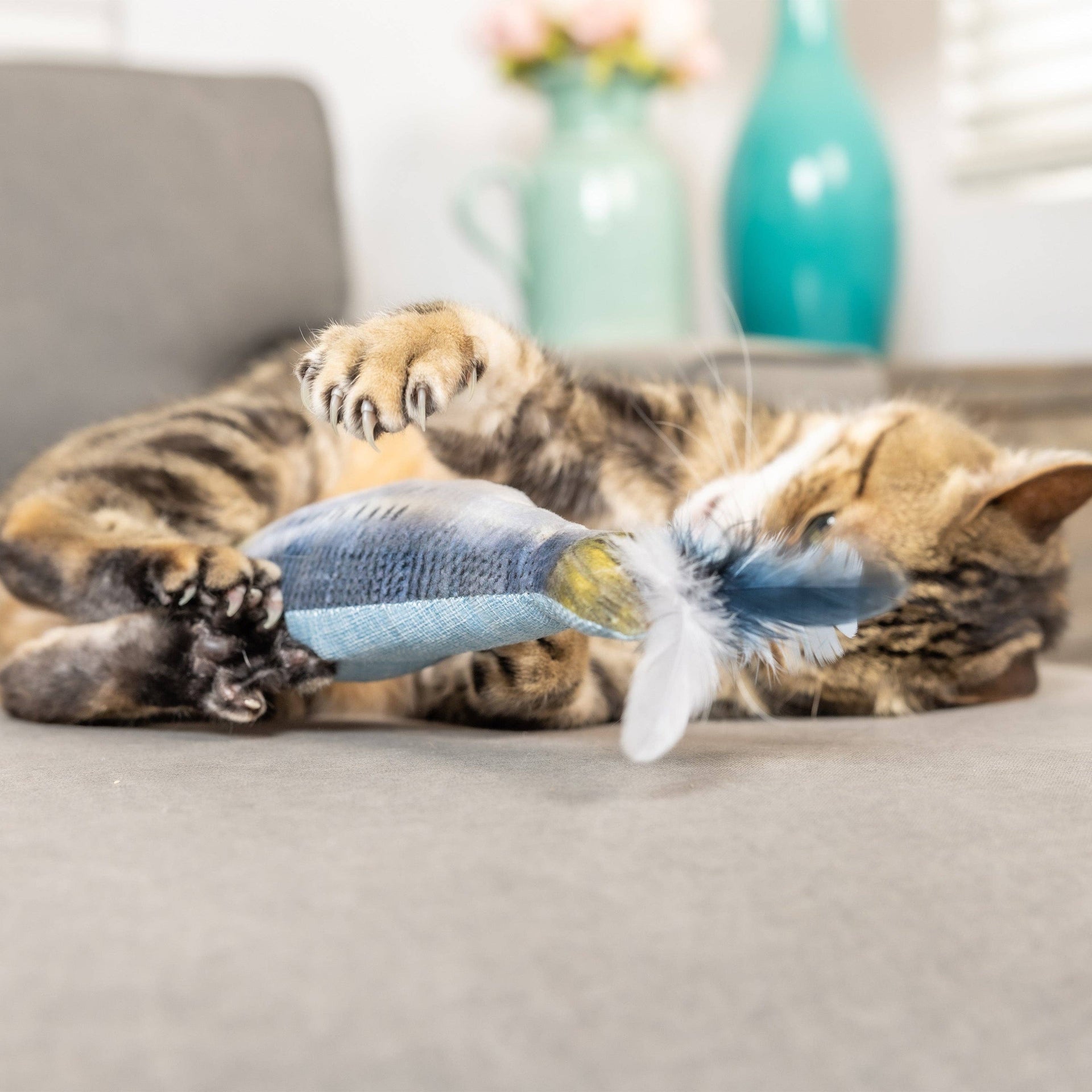 Huxley & Kent Sardine Kicker Cat Toy being played with by a cat demonstrating typical kicking behavior.