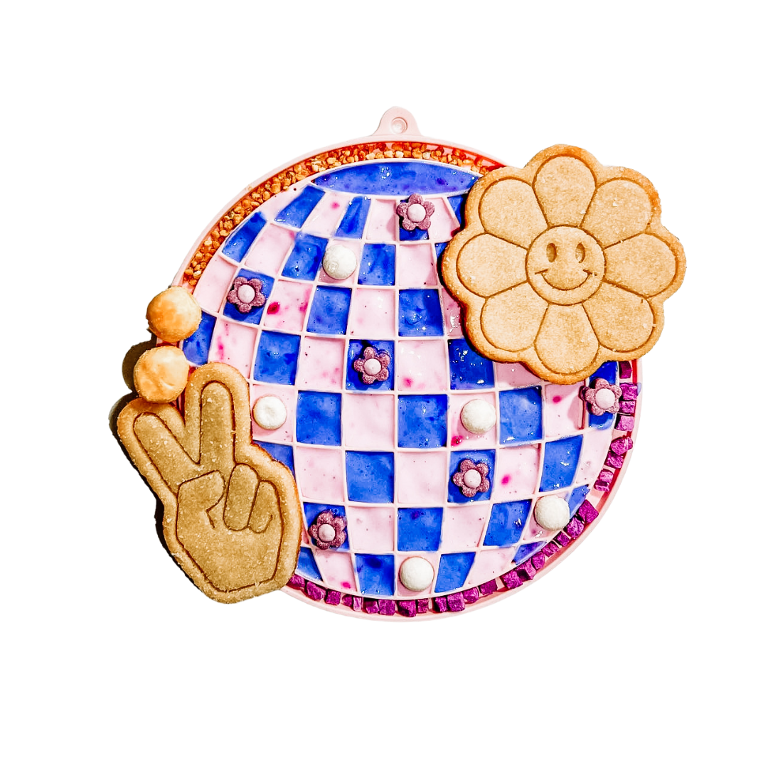 A dog licking treats from the blue Barks and Brownies Sea Licking Mat on a kitchen floor.