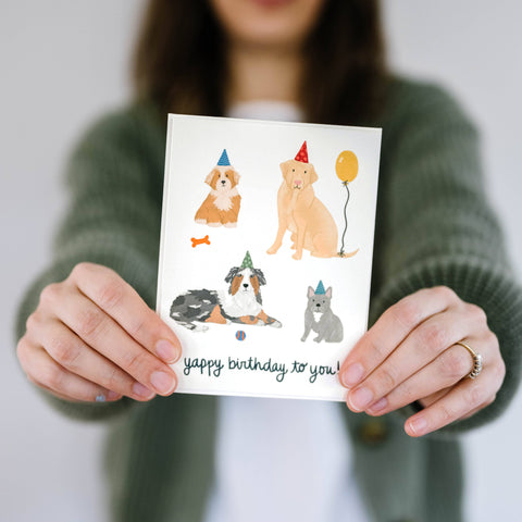 The Cheery Pet Yappy Birthday Card displayed with colorful party decorations and dog toys in celebratory arrangement.