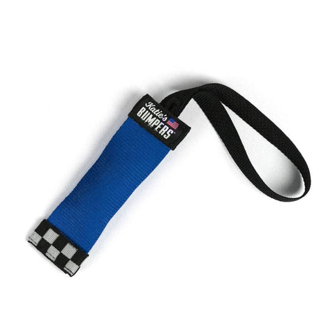 Katie's Bumpers Mini Sqwuggie 6-inch dog toy being carried by a small breed dog outdoors