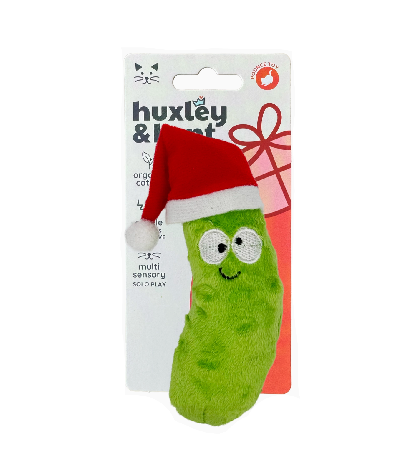 Green dog toy with a red Santa hat on a Huxley & Kent packaging.