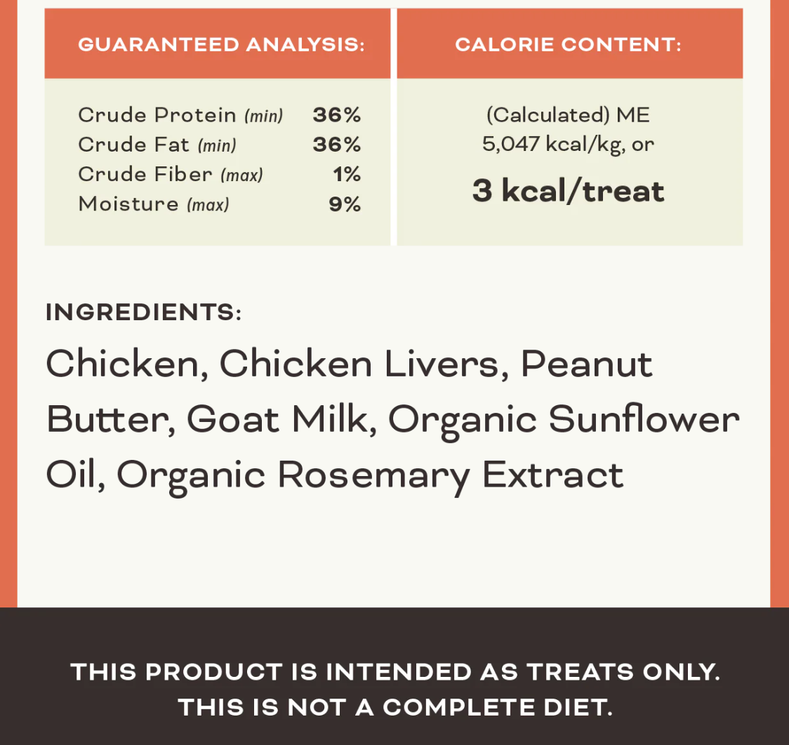 Primal Chicken & Peanut Butter freeze-dried dog treats scattered on rustic wooden surface showing texture and size.