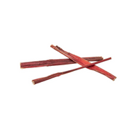 Happy dog chewing on a Redbarn Bully Skin Stick treat in a cozy home setting