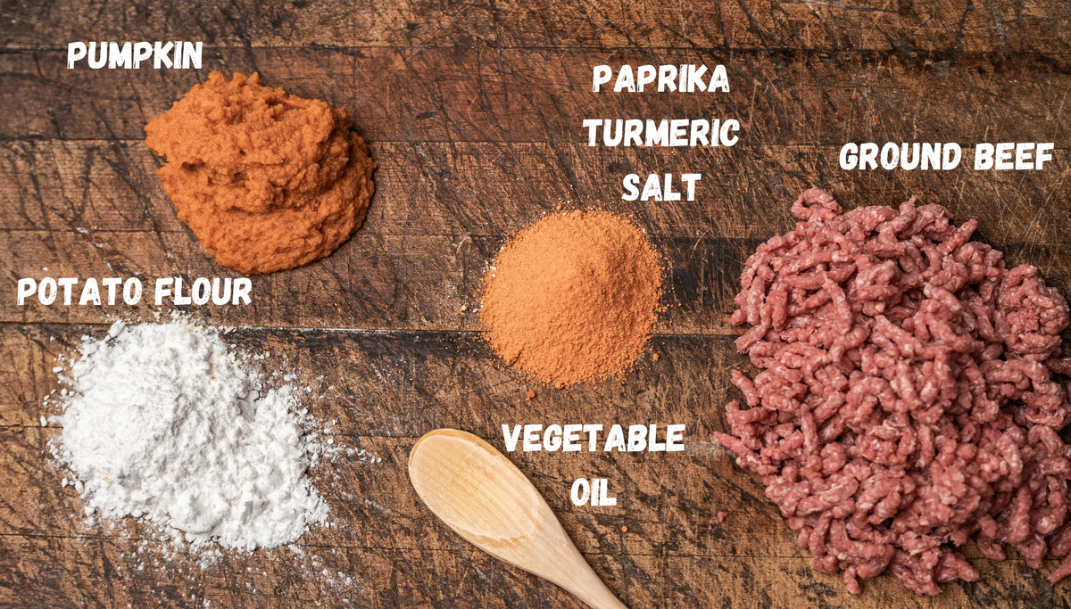 Dog Dish Saint Rocco's Treats ingredients including ground beef, pumpkin, potato flour, and spices on a wooden board.