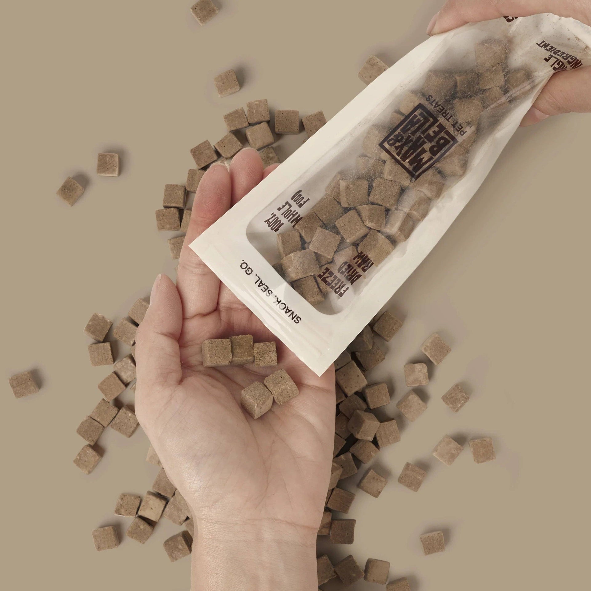 Dog Dish Max & Bella freeze-dried beef liver treats being poured from a resealable pouch into a hand.