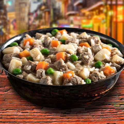 Dog Dish Fromm Family Frommbalaya chicken, vegetable, and rice stew in a bowl on a rustic wooden table.