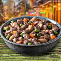 Dog Dish Fromm lamb stew with chunks of meat, carrots, peas, and potatoes in a rustic bowl on a wooden surface.