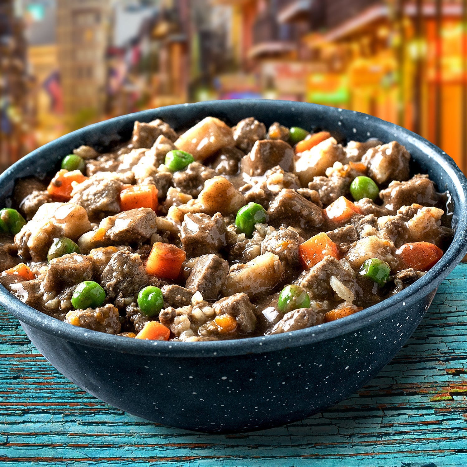 Dog Dish Fromm pork stew with carrots, peas, and potatoes in a dark speckled bowl on a rustic wooden table.