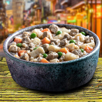 Dog Dish Fromm turkey stew with chunks of meat, potatoes, carrots, and peas in a speckled bowl on a rustic table.