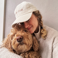 Dog Dish ivory corduroy Dog Mom baseball cap worn by a woman hugging her golden doodle dog