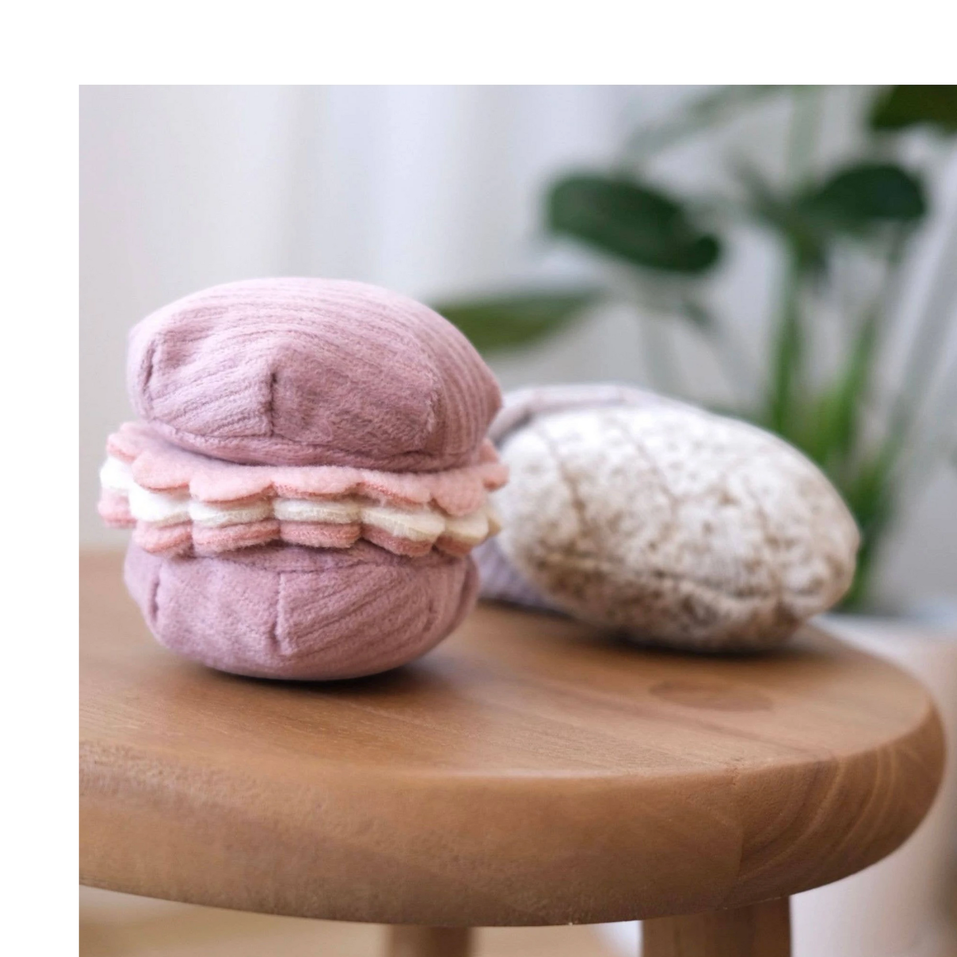 Dog Dish Lambwolf Cookie Enrichment Set featuring a pink macaroon and textured madeleine dog puzzle toys on a stool.