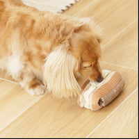 Dog Dish Lambwolf Eclair enrichment toy with cream flaps being sniffed by a long-haired dog on a wooden floor