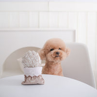 Dog Dish Lambwolf Cookie enrichment toy shaped like a madeleine with a poodle sitting at a table in the background.