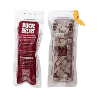 Dog Dish Max & Bella freeze-dried duck breast dog treat pouches with clear window showing cubed meat snacks.