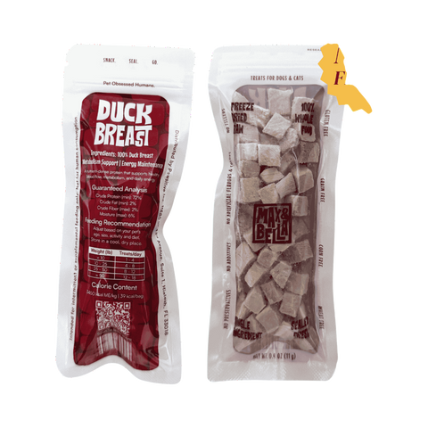 Dog Dish Max & Bella freeze-dried duck breast dog treat pouches with clear window showing cubed meat snacks.