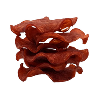 Dog Dish Wild Meadow Farms turkey crispy chips stacked in a wavy, thin-sliced pile against a black background.
